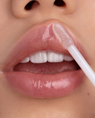 Model with light-medium skin wearing EM Cosmetics Crystal Lip Gloss for a high-shine, plump, and hydrated pout.
