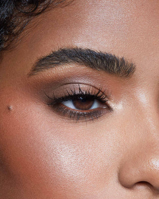 Model with dark skin wearing EM Cosmetics Divine Skies Palette in Da Vinci for a rich, warm bronze eye look.