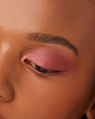 Model with dark skin wearing EM Cosmetics Divine Skies in Faded Clementine for a rich, warm sunset eye look.