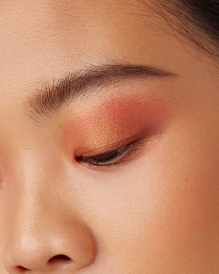 Model with medium skin wearing EM Cosmetics Divine Skies in Faded Clementine for a warm, radiant orange look.