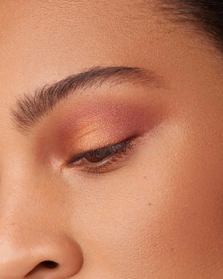 Model with medium skin wearing EM Cosmetics Divine Skies in Faded Clementine, creating a defined terracotta eye.