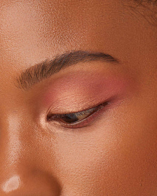 Model with dark skin wearing EM Cosmetics Divine Skies Eyeshadow in Magic Hour for a sunset-inspired look.