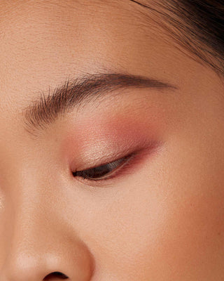 Model with medium skin wearing EM Cosmetics Divine Skies Eyeshadow in Magic Hour for a warm eye look.