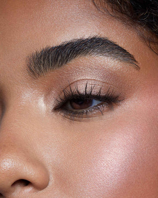 Model with dark skin wearing EM Cosmetics Divine Skies Palette in Rodin for a rich, deep cool-toned eye look.