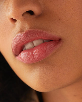Model with medium skin wearing EM Cosmetics Lip Cushion in Angele for a soft pink gloss.