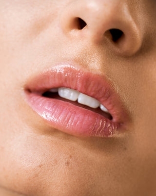 Model with light skin wearing EM Cosmetics Lip Cushion in Clear Quartz for a natural, dewy sheen.