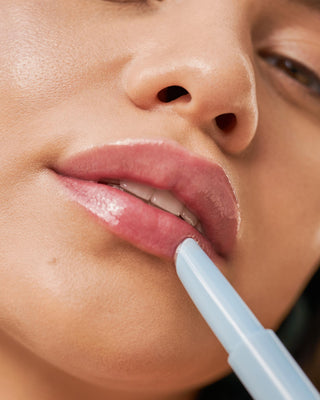 Model with medium skin wearing EM Cosmetics Lip Cushion in Clear Quartz for a hydrated, glossy lip look.