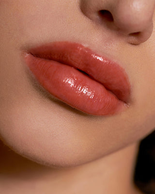 Model with light skin wearing EM Cosmetics Lip Cushion in Faded Clementine for a sheer orange tint.