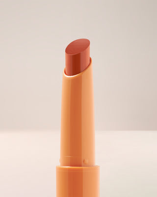 Close-up texture shot of EM Cosmetics Lip Cushion in Faded Clementine showing the glossy finish.