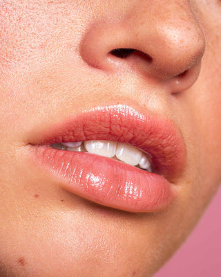 Model with light skin wearing EM Cosmetics Lip Cushion in Magic Hour for a luminous glow.