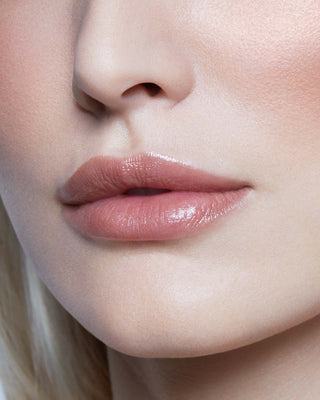 Model with light skin wearing EM Cosmetics Lip Cushion in Mona Lisa for a sheer, neutral brown tinted lip balm finish.