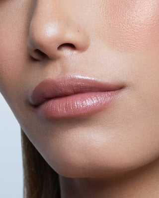 Model with medium skin wearing EM Cosmetics Lip Cushion in Mona Lisa for a hydrated, tinted warm nude lip look.