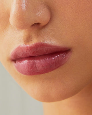 Model with light skin wearing EM Cosmetics Lip Cushion in Mystic for a glossy berry look.