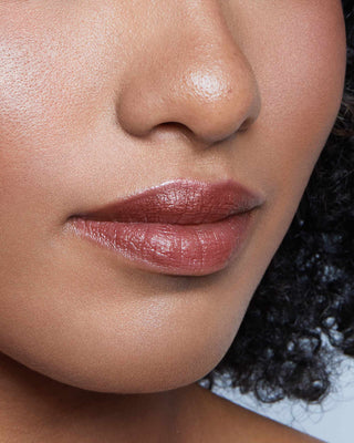 Model with dark skin wearing EM Cosmetics Lip Cushion in Van Gogh for a glossy, hydrated berry-rose lip look.