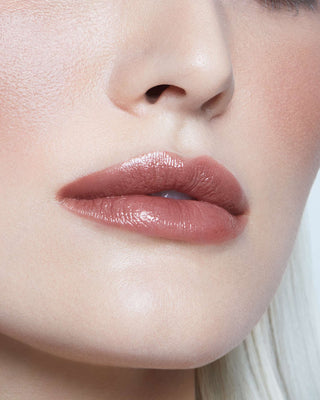 Model with light skin wearing EM Cosmetics Lip Cushion in Van Gogh for a sheer, rosy tinted lip balm finish.