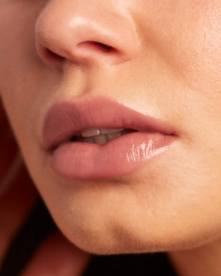 Model with light skin wearing EM Cosmetics Lip Cushion in Venetian Rose for a luminous look.