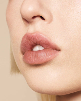 Model with light-medium skin wearing EM Cosmetics Phantom Blur Lip Tint in Monet for a soft, blurred cool-toned mauve finish.