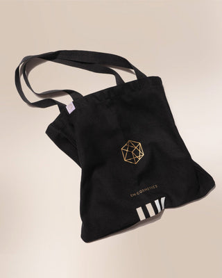 The official EM Cosmetics canvas tote bag, featuring a clean white design with the brand's elegant logo printed in black.