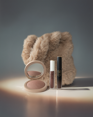 Editorial still life of EM Cosmetics blush and lip products in warm chocolate tones.