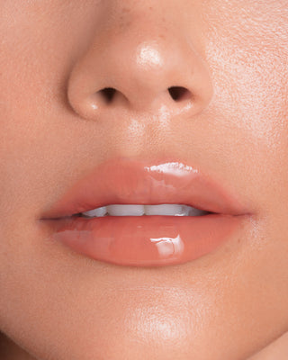 Model with light skin wearing EM Cosmetics Everglass Lip Dew in Dream for a glossy, sparkling clear lip look.