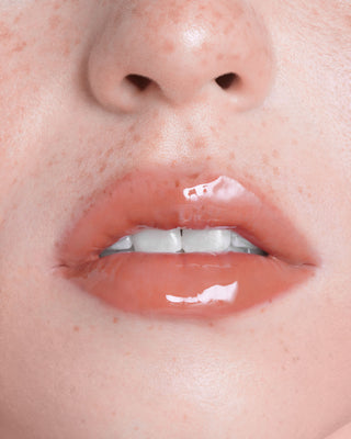 Model with medium skin wearing EM Cosmetics Everglass Lip Dew in Enchant for a glossy, deep berry lip look.