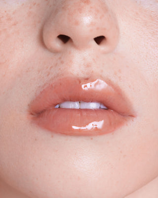 Model with medium skin wearing EM Cosmetics Everglass Lip Dew in Lullaby for a glossy, dusty rose lip look.