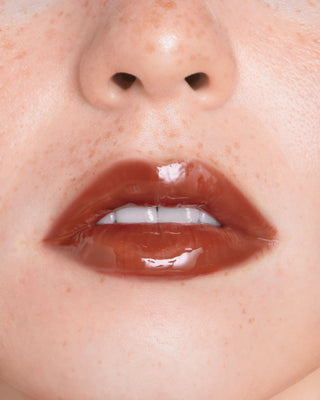 EM Cosmetics Everglass Lip Dew in Secret, a soft petal pink shade, shown in its sleek, minimalist packaging.