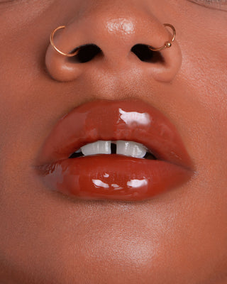 Model with medium skin wearing EM Cosmetics Everglass Lip Dew in Secret for a glossy, neutral pink lip look.