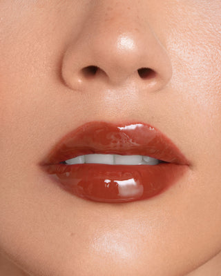 Model with light skin wearing EM Cosmetics Everglass Lip Dew in Secret for a glossy, pale pink lip look.