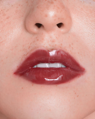 EM Cosmetics Everglass Lip Dew in Temptress, a rich berry shade, shown in its sleek, minimalist packaging.