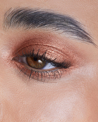 Model wearing EM Cosmetics Cosmic Pearl Eyeshadow in Helios for a warm, shimmering copper eye look.