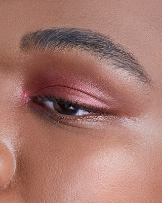 Model with dark skin wearing EM Cosmetics Cosmic Pearl Eyeshadow in Scorpius for a dramatic, metallic eye look.