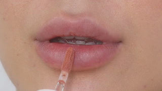 Model with light skin wearing EM Cosmetics Everglass Lip Dew in Enchant for a glossy, bright berry lip look.