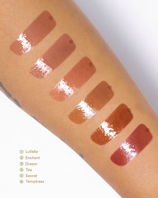 Arm swatches of EM Cosmetics Everglass Lip Dew, showing the high-shine, glassy finish of shade Secret.