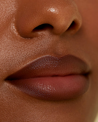 Model with dark skin wearing EM Cosmetics Soft Blur Lip Liner in Foxy for a warm, dimensional nude lip.