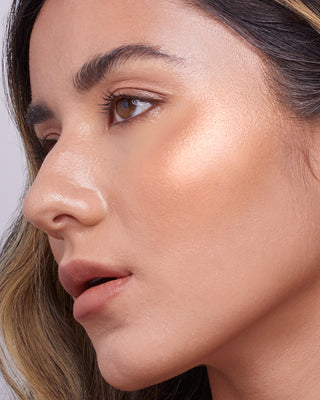 Model with medium skin wearing EM Cosmetics Sunscape Highlighter in Legendary for a sun-kissed, golden glow.