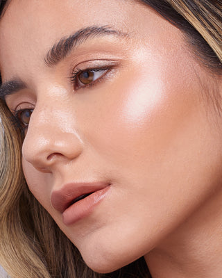 Model with medium skin wearing EM Cosmetics Sunscape Highlighter in Serenity for a warm, rosy highlight.